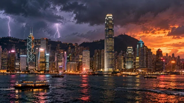 Asian financial district skyline at dusk with storm clouds and glass towers above a harbour