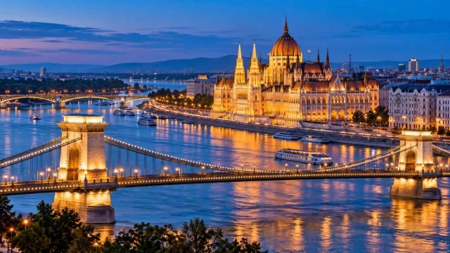 Danube riverfront in Budapest at blue hour with a lit grand parliament building and chain bridge