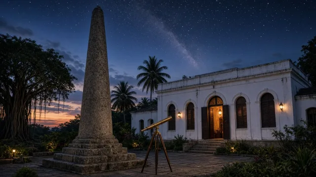 A tall granite pillar beside a whitewashed colonial observatory with arched doors, palms and a brass telescope on a tripod under a starry twilight sky in old Madras