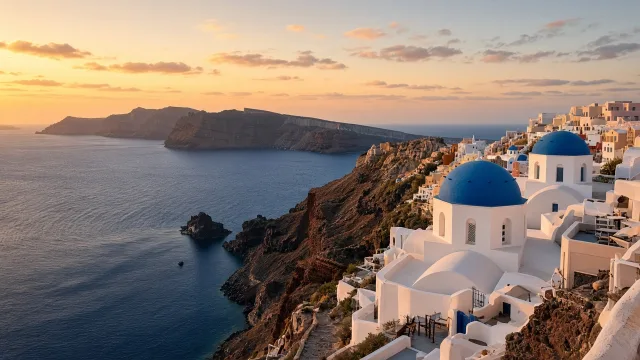 Whitewashed houses and blue-domed churches on Santorini's caldera cliffs at sunset