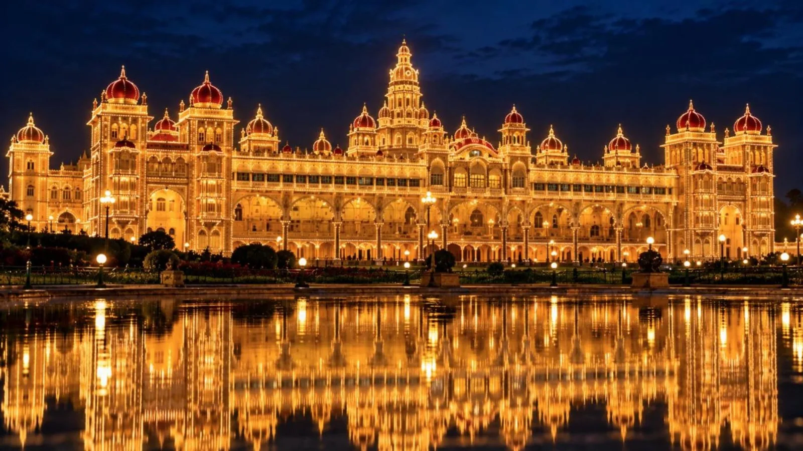 Mysore Palace lit up with thousands of lights at night and reflected in water