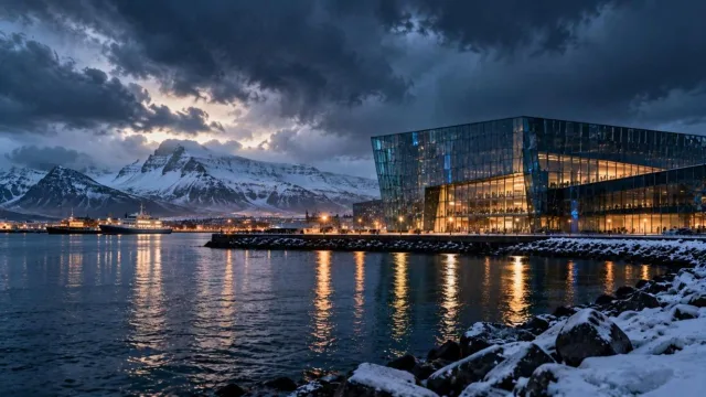 Stormy harbour with a modern glass building and snow-capped mountains in a dramatic Icelandic landscape