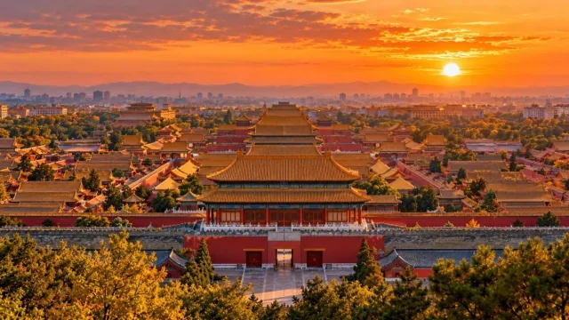 Golden roofs and red walls of the Forbidden City in Beijing seen from above at sunset