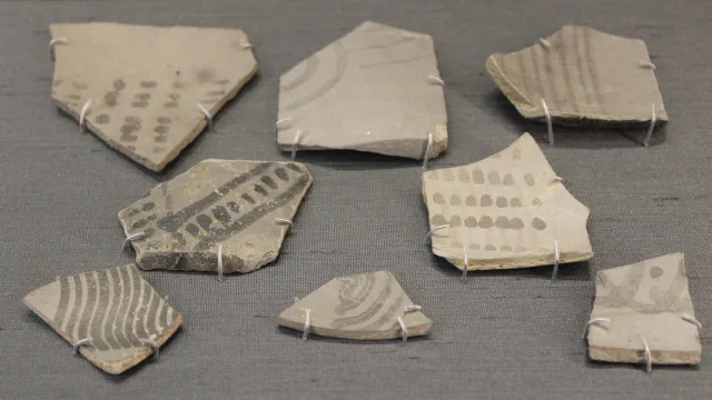 Fragments of Painted Grey Ware pottery from about 1000 BCE, light grey sherds painted with black dots, stripes and arcs, displayed on pins in the British Museum