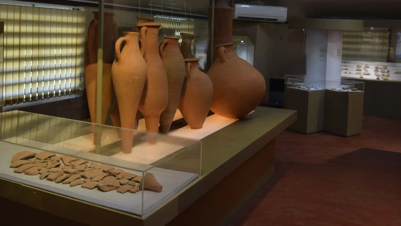 Mediterranean amphorae on display at the Pattanam excavation museum in Kerala, with excavated amphora sherds in a glass case in front