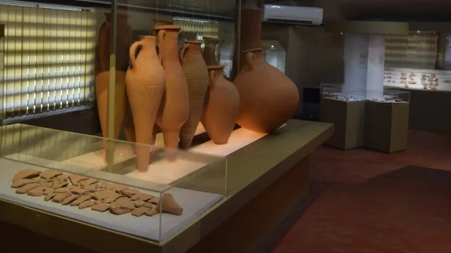 Mediterranean amphorae on display at the Pattanam excavation museum in Kerala, with excavated amphora sherds in a glass case in front