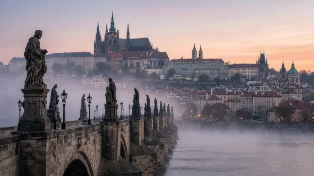 Charles Bridge with its statues and Prague Castle on the hill at dawn over the Vltava river